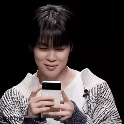 A Young Man Holding A Cell Phone In His Hands GIF