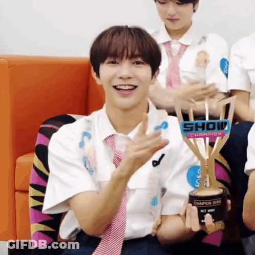 A Young Man Holding A Trophy That Says Show Champion On It GIF