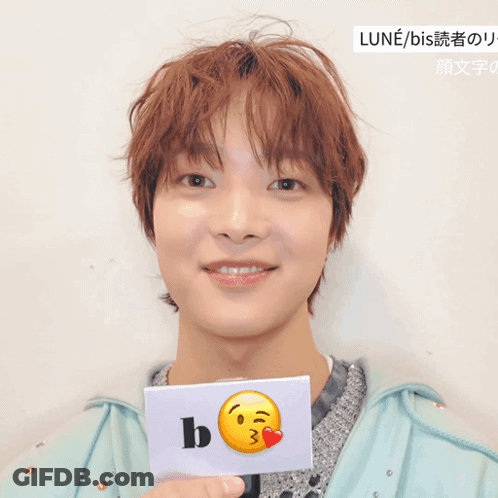A Young Man Holds A Card With A Smiley Face And The Letter B GIF