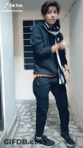 A Young Man In A Black Hoodie And Black Pants Is Standing In A Hallway With A Tik Tok Watermark On The Bottom Right GIF