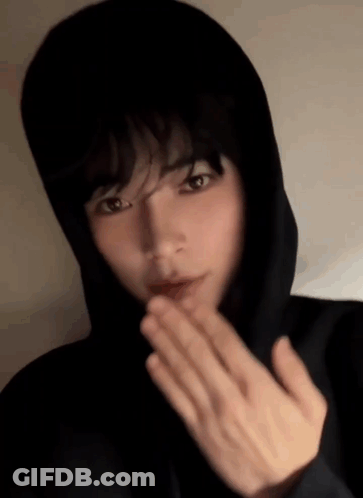 A Young Man In A Black Hoodie Is Blowing A Kiss GIF
