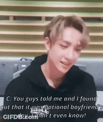 A Young Man In A Black Hoodie Is Sitting In Front Of A Window And Talking . GIF