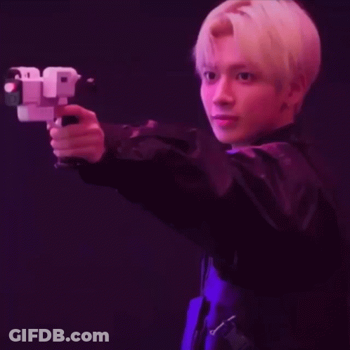 A Young Man In A Black Jacket Is Holding A Gun In His Hand . GIF
