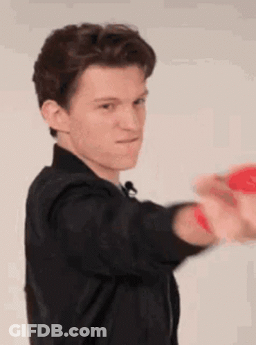 A Young Man In A Black Jacket Is Holding A Red Ball In His Hands . GIF