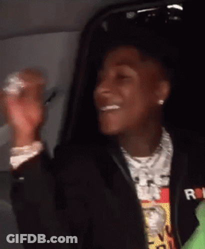 A Young Man In A Black Jacket Is Sitting In A Car And Smiling . GIF