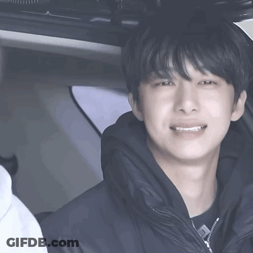 A Young Man In A Black Jacket Is Talking To Another Young Man In A Car GIF