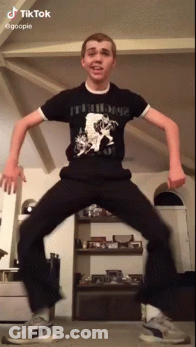 A Young Man In A Black Shirt And Black Pants Is Dancing In A Living Room . GIF