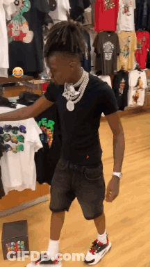 A Young Man In A Black Shirt And Shorts Is Standing In A Store GIF