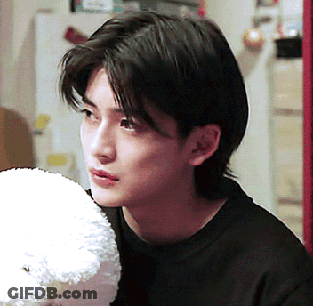 A Young Man In A Black Shirt Holds A Stuffed Animal GIF