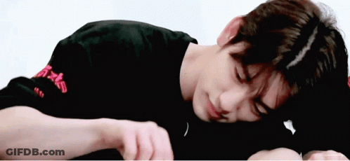A Young Man In A Black Shirt Is Laying On His Stomach . GIF