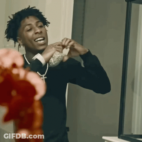 A Young Man In A Black Shirt Is Looking At Himself In The Mirror GIF