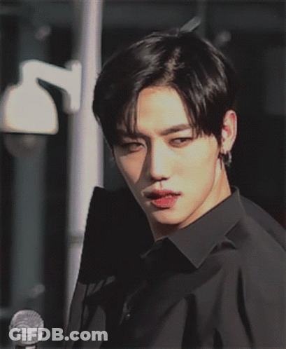 A Young Man In A Black Shirt Is Looking At The Camera GIF