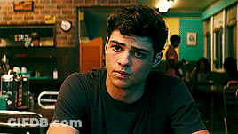 A Young Man In A Black Shirt Is Sitting At A Table In A Restaurant . GIF
