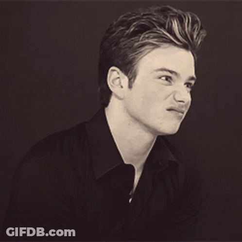 A Young Man In A Black Shirt Is Smiling GIF