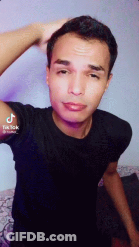 A Young Man In A Black Shirt Is Taking A Selfie . GIF