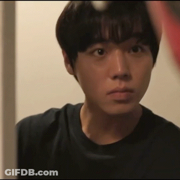 A Young Man In A Black Shirt Looks At Himself In A Mirror GIF