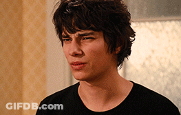 A Young Man In A Black Shirt Looks At The Camera With A Serious Look On His Face GIF