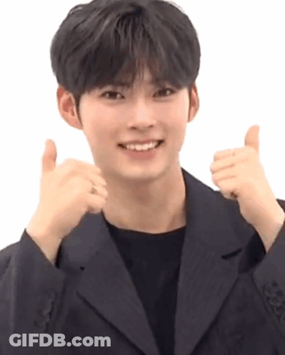 A Young Man In A Black Suit Is Giving A Thumbs Up . GIF