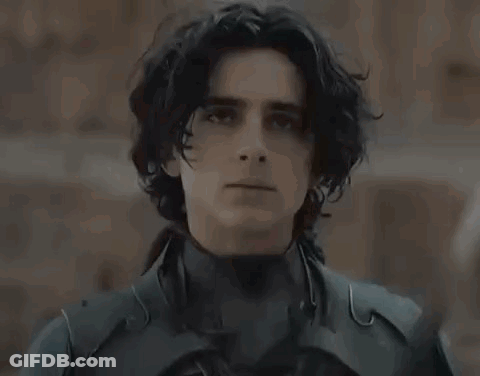 A Young Man In A Black Suit Is Holding A Sword In His Hand . GIF