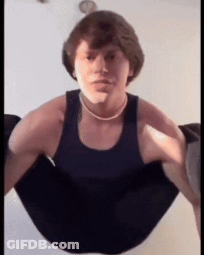 A Young Man In A Black Tank Top Is Doing A Handstand GIF