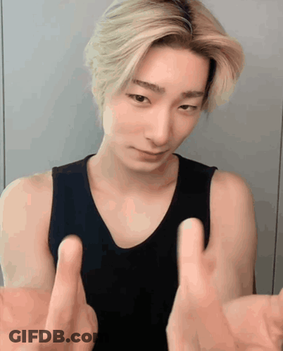 A Young Man In A Black Tank Top Is Making A Funny Face With His Hands Outstretched GIF
