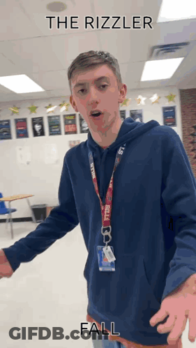 A Young Man In A Blue Hoodie Is Standing In A Classroom With The Words " The Rizzler Fall " Written Above Him GIF