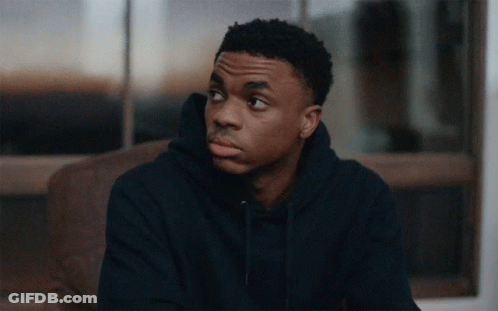 A Young Man In A Blue Hoodie Sits On A Couch Looking Out A Window GIF