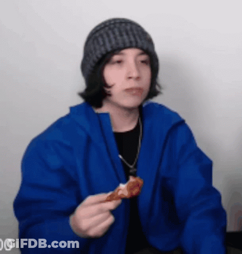 A Young Man In A Blue Jacket Is Eating A Piece Of Pizza . GIF