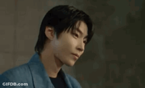 A Young Man In A Blue Jacket Is Looking Down . GIF