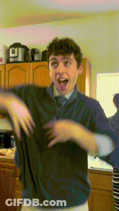 A Young Man In A Blue Shirt And Tie Is Dancing In A Kitchen GIF