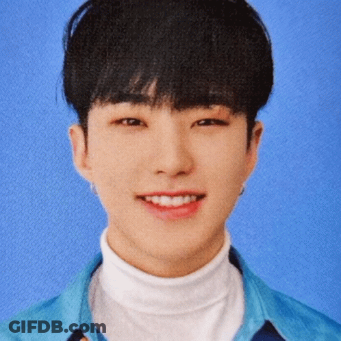 A Young Man In A Blue Shirt And White Turtleneck Smiles GIF