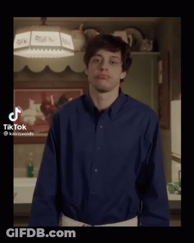A Young Man In A Blue Shirt Is Standing In A Kitchen With His Arms Outstretched . GIF