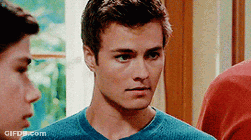 A Young Man In A Blue Shirt Is Standing Next To Another Young Man . GIF