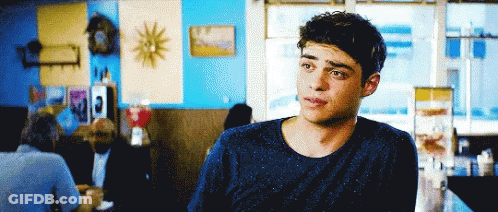 A Young Man In A Blue Sweater Is Sitting At A Table In A Restaurant GIF