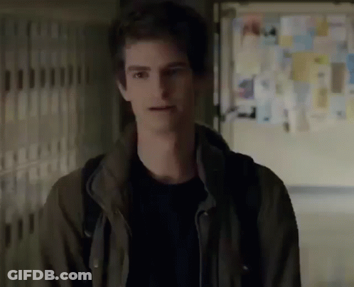 A Young Man In A Brown Jacket Is Standing In A Hallway With A Backpack . GIF