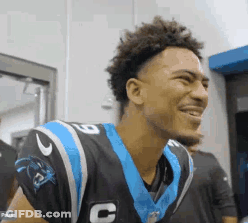 A Young Man In A Carolina Panthers Uniform Is Smiling And Laughing . GIF