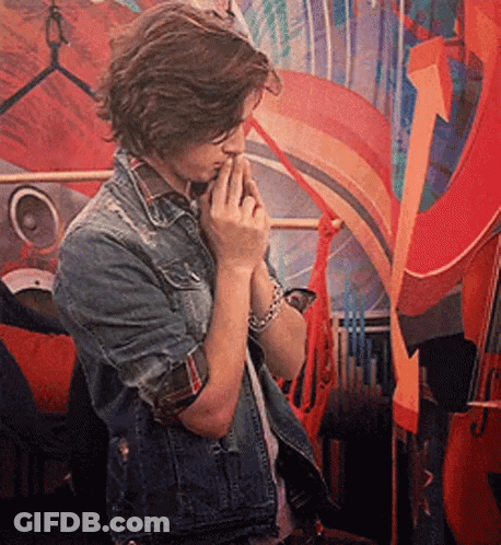 A Young Man In A Denim Jacket Is Standing In Front Of A Colorful Painting GIF