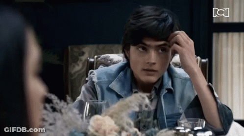 A Young Man In A Denim Vest Sits At A Table With A Woman GIF