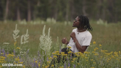 A Young Man In A Field Of Flowers Wearing A Boy Shirt GIF