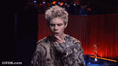 A Young Man In A Floral Shirt Is Pointing At Something GIF