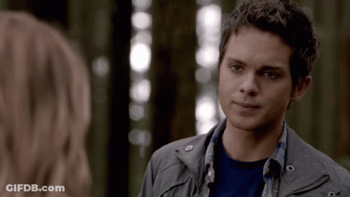 A Young Man In A Gray Jacket Is Looking At A Woman GIF