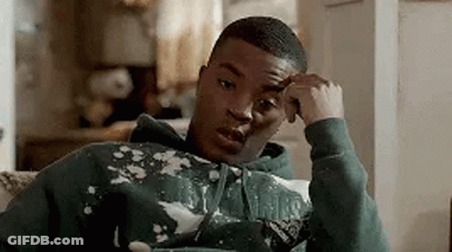 A Young Man In A Green Hoodie Is Sitting On A Couch . GIF