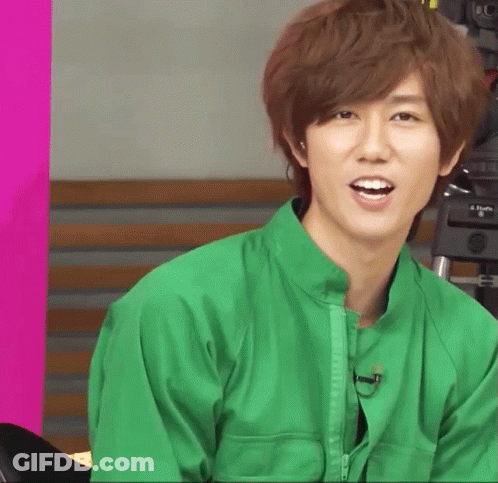 A Young Man In A Green Jacket Is Smiling GIF