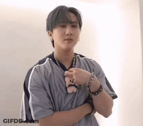 A Young Man In A Grey Shirt Is Holding A Stuffed Animal . GIF