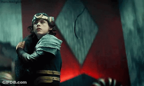A Young Man In A Knight 'S Armor Is Holding A Sword In Front Of A Red Wall . GIF