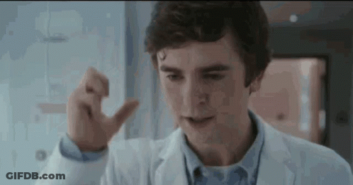 A Young Man In A Lab Coat Is Pointing At Something . GIF