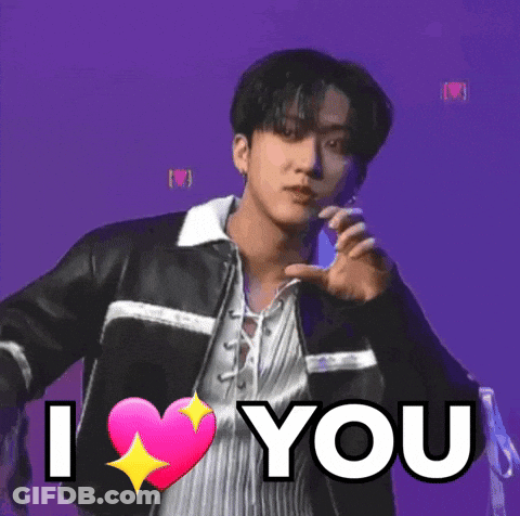 A Young Man In A Leather Jacket Is Holding A Pink Heart And Says `` I Love You '' . GIF