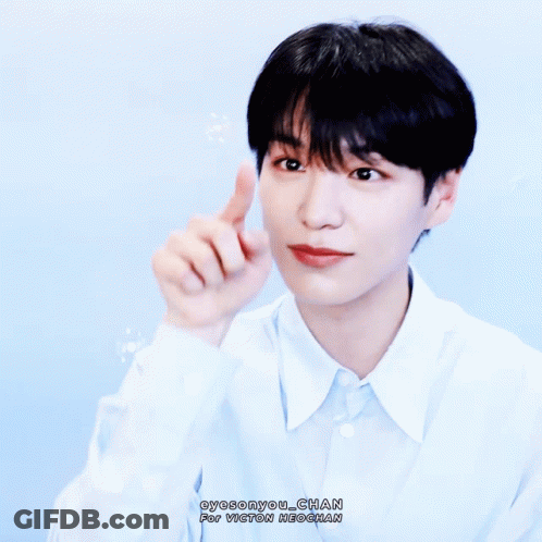 A Young Man In A Light Blue Shirt Is Pointing His Finger Up GIF