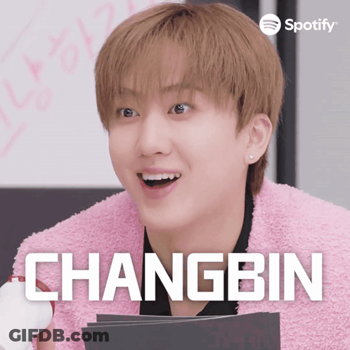 A Young Man In A Pink Jacket With The Name Changbin On The Bottom GIF