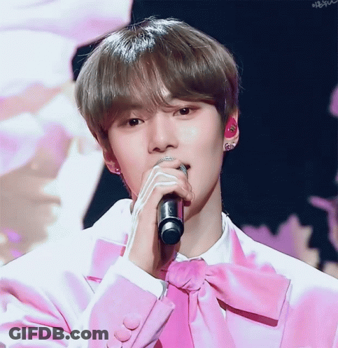 A Young Man In A Pink Suit Sings Into A Microphone GIF